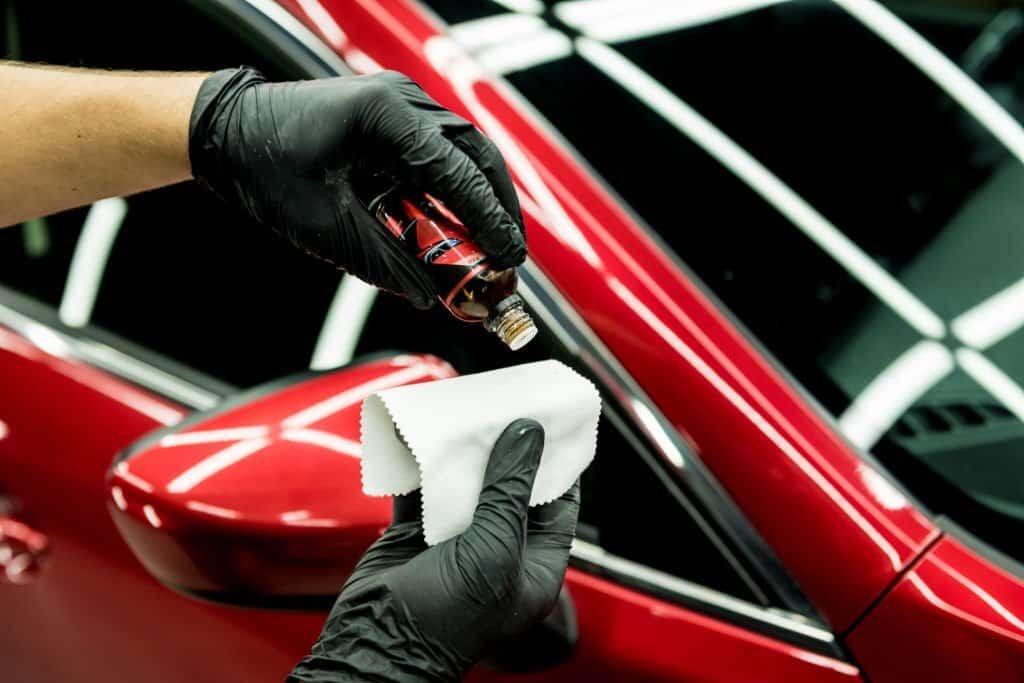 Car service worker applying ceramic coating on a car